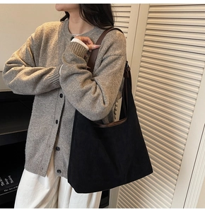 Detail of black suede tote bag with brown leather shoulder strap for casual commuting