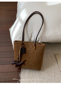 Detailed close-up of a retro brown frosted suede tote bag with a cute dachshund charm