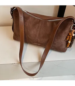 Vue détaillée du sac en daim marron avec bandoulière en cuir et charm en bois