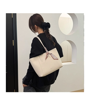 Detail view of cream tote bag with patterned scarf handle and embossed logo text