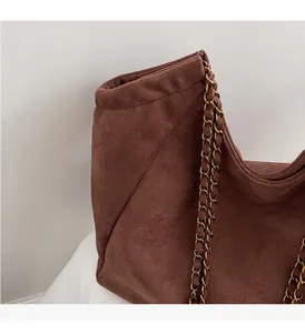 Détails de la texture suédine marron et de la chaîne dorée sur le grand sac cabas