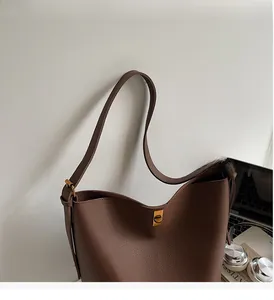 Vue macro détaillée du cuir marron café à grain lychee et du fermoir rotatif doré du sac