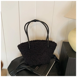 Detail of black faux fur tote bag with plush texture and long cylindrical handles