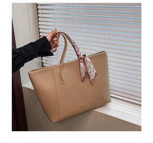 Macro detail of khaki litchi grain leather tote bag with floral scarf on handle