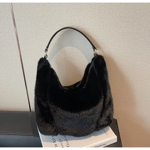 Close-up of black faux fur hobo bag with sleek leather strap and metallic rings