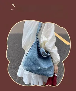 Détail du cabas vintage en denim avec lettrage blanc et poignées de transport