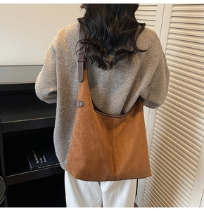 Detail of a large brown matte faux suede tote bag with adjustable leather shoulder strap