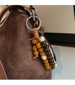 Gros plan du pendentif ethnique sur le sac bandoulière en daim marron foncé