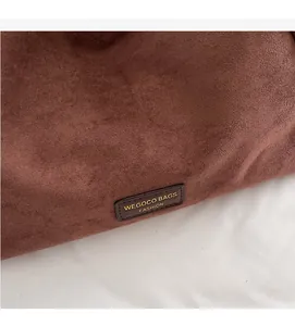 Gros plan détaillé sur la texture en daim marron foncé et l'étiquette en cuir du sac