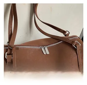Detailed macro view of silver zippers and hardware on the brown leather cylinder bag
