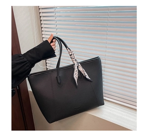 Close-up of black lychee texture tote bag featuring a decorative printed silk scarf handle