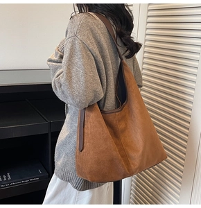 Close-up of brown matte suede hobo bag with dark leather strap worn by a model