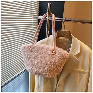 Detail of pink plush tote bag with beaded handle, paired with a beige blazer in soft light