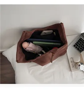 Vue intérieure du grand sac cabas en daim marron montrant les compartiments et poches