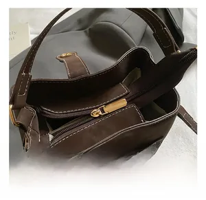 Detailed top view of dark brown leather bucket bag with golden zipper and metal hardware