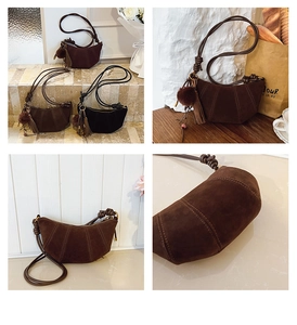 Detail of nubuck leather crescent bag with decorative stitching and tassel charm