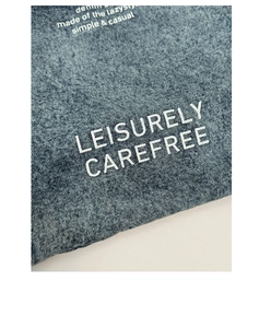 Détail de la texture denim bleu foncé et de l'impression blanche sur le sac cabas