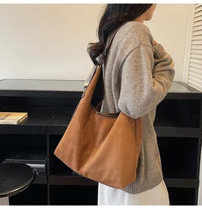 Brown suede tote bag with leather strap shown as oversized casual shoulder style on model