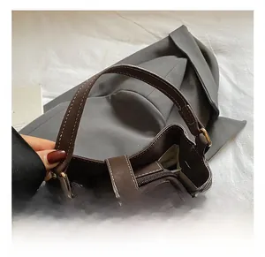 Detail of dark brown leather bucket bag handle with white contrast stitching and zip pocket