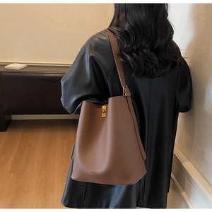 Détail d'un sac seau en cuir grainé marron avec boucles dorées et logo gravé