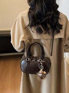 Chic dark brown faux leather bowling bag with plush charm and crossbody strap