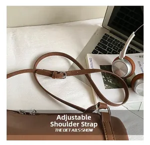 Detail of adjustable leather strap with silver metal buckle on a brown tote bag