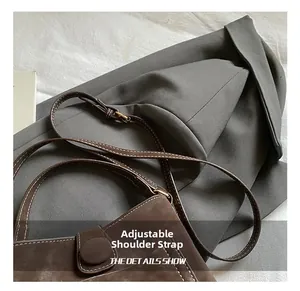 Detail of adjustable leather strap and magnetic buckle on brown suede crossbody bag