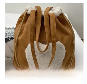 Detail of brown suede bucket bag featuring white plush heart applique and drawstrings
