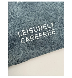 Detail of washed blue denim fabric texture with white LEISURELY CAREFREE print