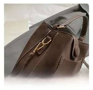 Detail of dark brown bucket bag with gold hardware and white contrast stitching