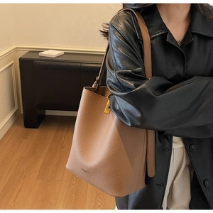 Détail du grand sac seau en cuir marron avec texture litchi et boucle dorée élégante