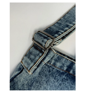 Adjustable denim shoulder strap detail with metal buckle and orange stitching accents
