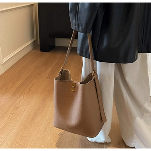 Détail du cuir grainé café et du fermoir doré vintage sur ce sac seau élégant