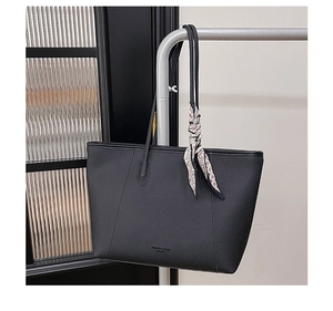 Detail of black lychee grain leather tote bag with elegant floral silk scarf on handle