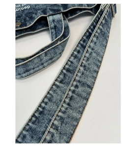 Detailed macro view of vintage denim bag strap with reinforced stitching and metal hardware