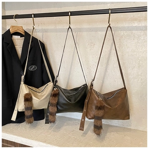 Detailed view of three minimalist hobo bags with removable striped faux fur pendants