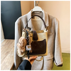 Detail view of MERRIL beige bucket bag with brown pocket and plush bear charm