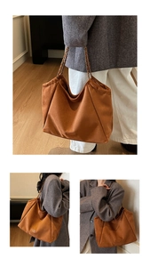 Détail du cabas en daim marron avec bandoulière en chaîne et logo embossé élégant