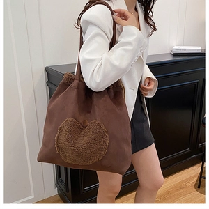 Detailed view of dark brown suede tote bag featuring a cozy plush heart applique