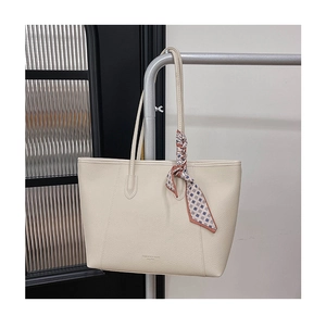 Close-up of cream leather tote bag with lychee texture and decorative silk scarf detail