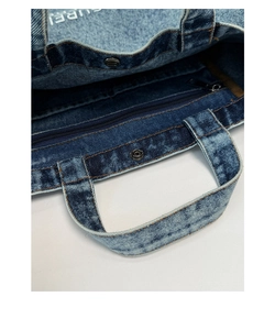 Detail of denim tote bag with metal snap button and interior zippered pocket