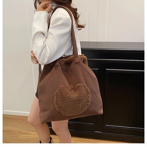 Detail of a large brown suede tote bag with a plush heart pocket worn on the shoulder