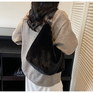 Detailed view of black faux fur shoulder bag with leather strap on a grey sweater