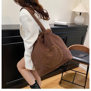 Detailed view of brown suede bucket bag with plush heart applique and drawstring closure