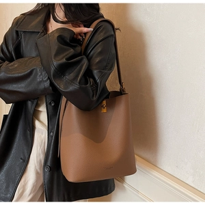 Détail du sac seau en cuir caramel avec texture grainée et fermoir en métal doré