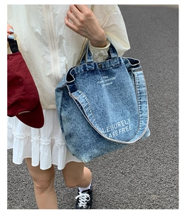 Détail du sac cabas en denim délavé bleu avec texte blanc sur fond urbain de haute qualité
