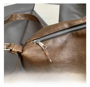 Detail of silver zipper and brown faux fur pompom charm on a brown leather handbag