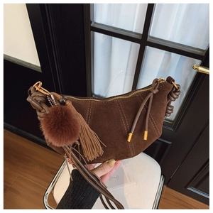 Detail of dark brown suede dumpling bag with tassel and pompom charm decoration