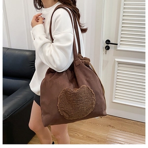 Detail of dark brown suede tote bag featuring a plush lamb wool heart patch on the front