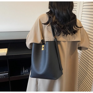 Détail d'un sac seau en cuir noir grainé avec boucle dorée et fine bandoulière en cuir